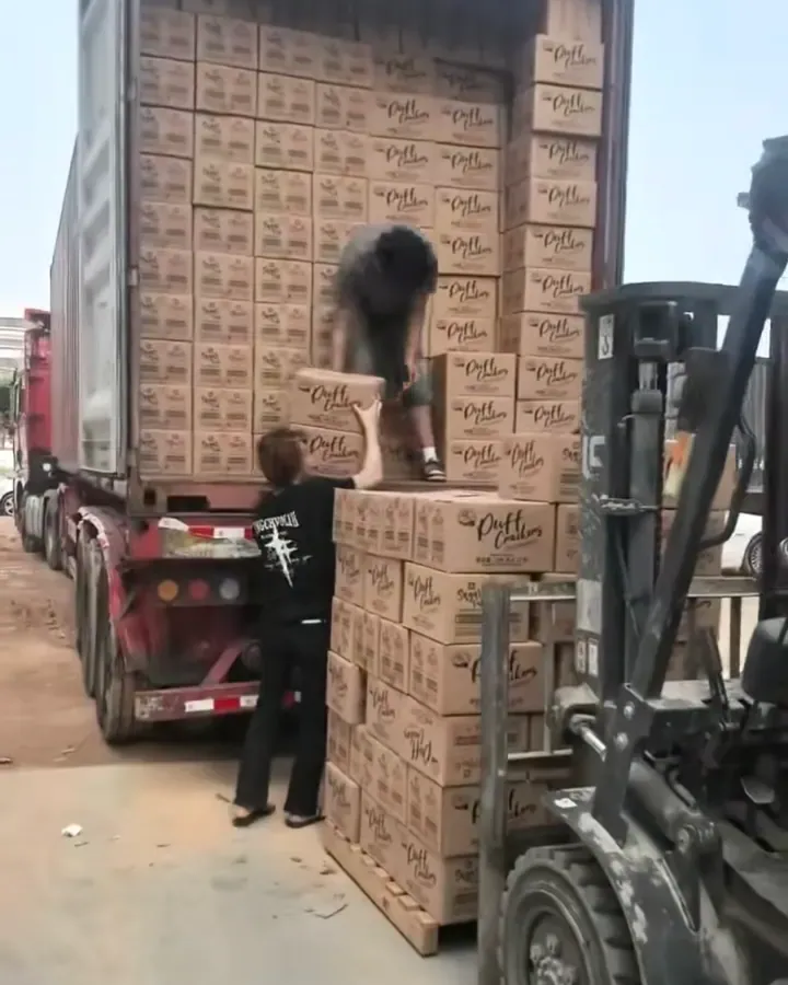 Workers loading boxed snack products into a shipping container